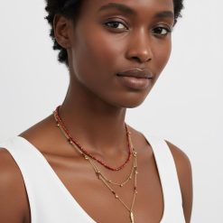 colliers à petit pois breloques poissons multi rangs doré porté par une femme avec des perles rouges corail et un pendentif en forme de poisson