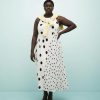 robes asymétriques à pois dos nageur ourlet variés mi longue noirs blanche portée par un mannequin avec un pull jaune noué sur les épaules