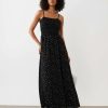 robes noires à pois blancs en tulle sans manches mi-longue portée par un mannequin sur un fond bleu avec un col rond et un ourlet à volant
