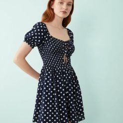 robes à pois marine caraco fente longue volants bleu blazer portée par un mannequin femme avec une robe longue noire à pois et volants