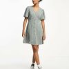 robes vintages rouges à pois verts boutonnée patineuse courte manches courtes col en v imprime floral vert et blanc portee par une femme avec des baskets