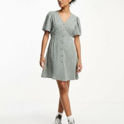 robes vintages rouges à pois verts boutonnée patineuse courte manches courtes col en v imprime floral vert et blanc portee par une femme avec des baskets