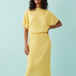 robes à pois jaune longue plissée épaules dénudées motif métallisé portée par une mannequin sur fond bleu clair