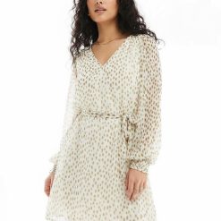 robes à pois transparentes courte col v nouée taille bouleau nori blanc et doré à manches longues portée par un mannequin aux cheveux bouclés