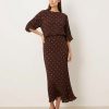 robes à pois jaune longue plissée épaules dénudées métallisé marron portée par un mannequin avec des escarpins foncés sur fond neutre