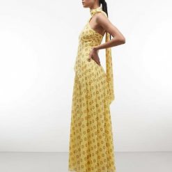 robes à pois jaune amovible détail foulard structurée taille longue style art déco portée par un mannequin de profil avec un col montant et un pan drapé dans le dos