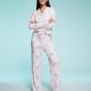 pyjamas à pois rose et nœuds pantalon ensemble ultra doux exclusivité porté par une jeune femme posant sur un fond bleu clair