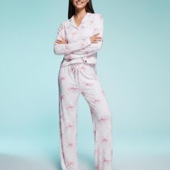 pyjamas à pois rose et nœuds pantalon ensemble ultra doux exclusivité porté par une jeune femme posant sur un fond bleu clair