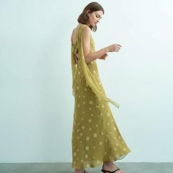 robes à pois jaune longue jacquard habillée dos ouvert portée par une femme de profil avec drapés fluides aux épaules