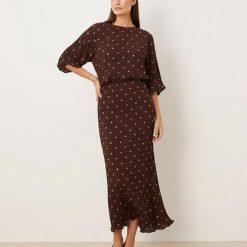 robes à pois jaune longue plissée épaules dénudées métallisé marron portée par un mannequin avec des escarpins foncés sur fond neutre