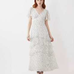 robes longues noires à pois en mousseline et volants couleur crème portée par un mannequin aux cheveux roux avec un col en v