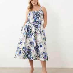 robes roses à pois blanc fines bretelles trapèze coupe corset imprimé fleuri bleu et violet portée par un mannequin sur fond bleu clair