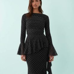 robes en tulle à pois volantés longue détails fronces noire à manches longues évasées portée par une mannequin sur fond bleu