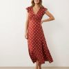 robes à pois rouge évasés col v et mancherons longue fluide portée par une femme avec une fente sur la jambe et boutonnière sur le décolleté