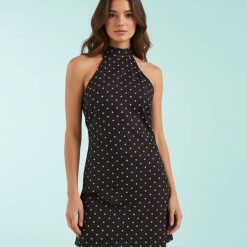 robes à pois jaune marron courte et dos nu portée par un mannequin sur fond bleu clair