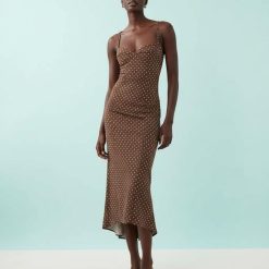 robes évasées à pois ourlet nu avec dos marron longue ajustée à bretelles fines portée par une mannequin sur fond bleu