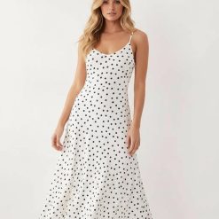 robes asymétriques à pois longue encolure dégagée beige ourlet midi femme élégante bretelles fines pois noirs fond blanc silhouette ajustée