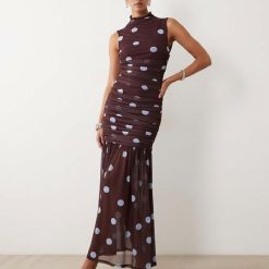 robes à pois rouge froncée basse taille encolure montante bordeaux sans manches imprimée de pois bleus portée par un mannequin