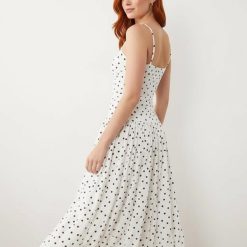 robes évasées à pois bretelles avec et jupe mi-longue fines robe blanche à pois noirs portée par une femme aux cheveux roux et souriante trouve parfaitement son style