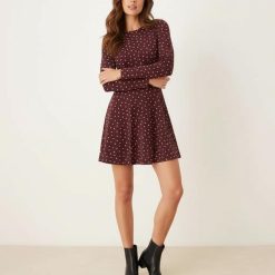 robes à pois rouge longues manches courte avec bordeaux imprimé petits pois blancs portée avec des bottines noires sur fond neutre