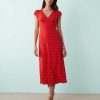 robes longues à pois rouge fluide col v avec mancherons portée par une femme élégante avec des sandales beiges sur un fond bleu