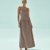robes longues marron à pois chocolat bretelles fines lin découpe côté portée par un mannequin avec des lunettes de soleil et des sandales blanches sur un fond bleu clair