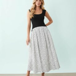robes roses à pois blanc longue hybride encolure dégagée sans manches élégante femme souriante posant avec une jupe à pois noirs et un haut noir