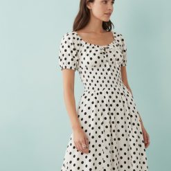 robes à pois blanc et noir longue plage manches bouffantes liens devant portée par une femme avec décolleté froncé et bustier smocké