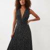 robes à pois blanc et noir froncée col longue v profond taille marquée sans manches portée par une femme aux cheveux bouclés