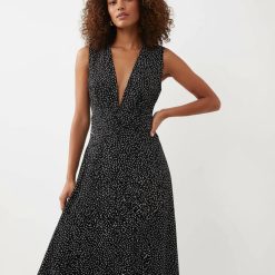 robes à pois blanc et noir froncée col longue v profond taille marquée sans manches portée par une femme aux cheveux bouclés
