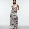 robes à pois blanc et noir froncé corsage longue taille basse bandeau portée par un mannequin sur fond blanc avec des sandales noires