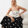 robes à pois blanc et noir occasions fines bandeau grandes bretelles multicolore portée par une femme blonde assise sur un canapé blanc