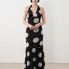 robes longues noires à pois corset style cintrée taille sirène ourlet evase avec decollete halter plongeant et motif a grands pois gris portee par un mannequin sur fond blanc