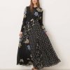 robes longues noires à pois imprimé fleuri col nageur avec manches ourlet godets portée par une femme avec des sandales noires