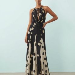 robes à pois années 50 noirs col bénitier profond longue imprimée godets contrastants portée par un mannequin sur fond bleu