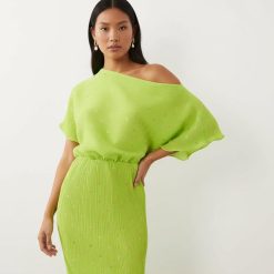 robes asymétriques à pois citron vert métallisés épaule plissée longue dénudée d’une femme asiatique portant une élégante robe longue à pois dorés une tenue chic et tendance