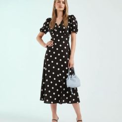 robes à pois jaune v col avec milongue marron chocolat portee par un mannequin avec un sac bleu