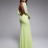 robes longues à petit pois encolure bateau dos ouvert manches agrume sur une mannequin à la peau foncée et aux cheveux noirs foncés qui porte la robe longue dun vert citron clair avec de petits pois blancs et un décolleté plongeant le dos est mis en valeur la mannequin regarde par-dessus son épaule droite sur un fond gris neutre léclairage met en valeur les détails et la texture de la robe lexpression de la mannequin est élégante et séduisante et ses cheveux sont longs et lisses