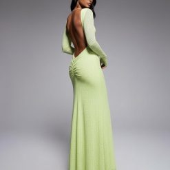 robes longues à petit pois encolure bateau dos ouvert manches agrume sur une mannequin à la peau foncée et aux cheveux noirs foncés qui porte la robe longue dun vert citron clair avec de petits pois blancs et un décolleté plongeant le dos est mis en valeur la mannequin regarde par-dessus son épaule droite sur un fond gris neutre léclairage met en valeur les détails et la texture de la robe lexpression de la mannequin est élégante et séduisante et ses cheveux sont longs et lisses