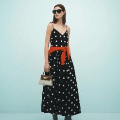 robes évasées à pois bouffante jupe coupée en biais trapèze mono longue robe noire a bretelles fines avec motifs a pois blancs et un pull orange noue a la taille