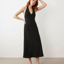 robes à petit pois noir dos nu et blanc longue et élégante portée par une femme aux cheveux roux avec des tongs noires