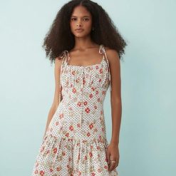 robes longues à pois rouge motif fleuri coton satiné liens buste courte blanche a bretelles nouees et volants portee par un mannequin