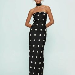 robes longues noires à pois bandeau en satin col foulard moulante sans bretelles portée par une femme avec des escarpins noirs