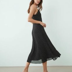 robes longues noires à pois fines bretelles fente cuisse fluide avec dentelle au decollete portee par une femme avec des talons beige