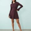 robes manches longues à pois violets bateau stretch patineuse courte encolure ronde portée par un mannequin sur un fond bleu clair