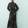 robes manches longues à pois nœud lavallière imprimé abstrait longue fluide noire et beige portée par un mannequin sur fond bleu clair