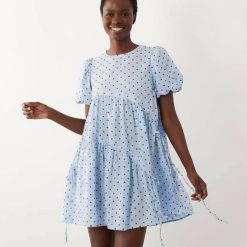 robes bleu ciel à pois crépon bouffantes courte asymétrique cordon serrage manches courtes portee par une femme sur fond neutre