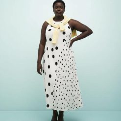 robes asymétriques à pois dos nageur ourlet variés mi longue noirs blanche portée par un mannequin avec un pull jaune noué sur les épaules