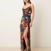 robes a pois bleu marine et fleurs longue fendue satin dos ouvert portee par un mannequin de profil avec des bretelles croisees dans le dos