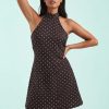 robes à pois jaune marron courte petite dos nu col montant sans manches forme trapeze portée par une femme avec fond bleu clair